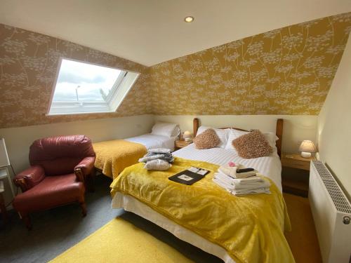a bedroom with two beds and a chair and a window at Aquarius B&B in Newquay