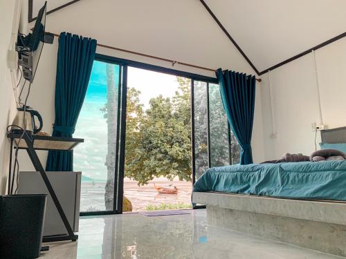 Schlafzimmer mit einem Bett und einer großen Glasschiebetür in der Unterkunft Mook tawan Beach house in Ko Mook