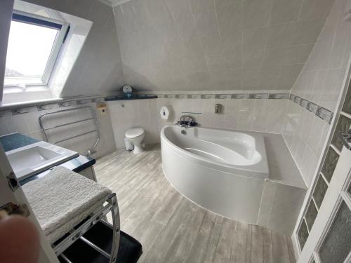 a white bathroom with a tub and a toilet at Aquarius B&B in Newquay
