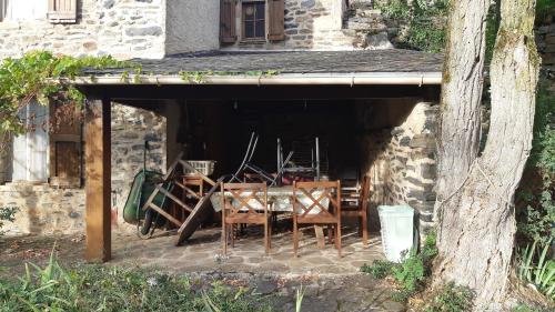 un groupe de chaises et de tables sous un bâtiment dans l'établissement Maison de caractère, à Viala-du-Tarn