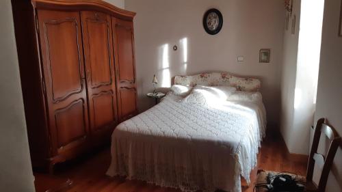 une chambre avec un lit blanc et une armoire en bois dans l'établissement Maison de caractère, à Viala-du-Tarn