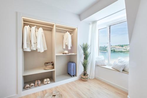 einen begehbaren Kleiderschrank mit weißer Kleidung und einem Fenster in der Unterkunft Hotel del Mar in Sanxenxo