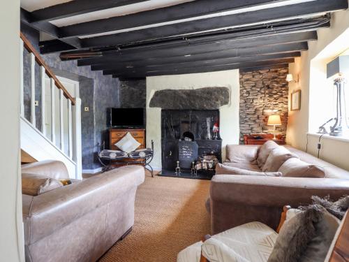 a living room with couches and a stone fireplace at Neuadd Wen in Derwen