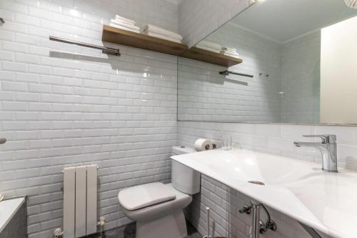 a white bathroom with a toilet and a sink at Victorooms in Bilbao