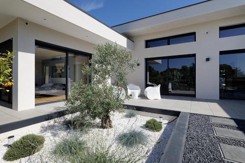 une maison avec deux chaises blanches devant dans l'établissement Maison d'Architecte BAIA piscine plein sud Uzès, à Uzès