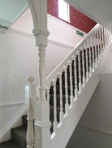 a staircase with white railings and a red wall at Ty Castell Guest House in Caerphilly