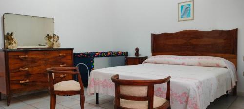 sypialnia z łóżkiem z komodą i 2 krzesłami w obiekcie Il Villino della Nonna w mieście Arbus