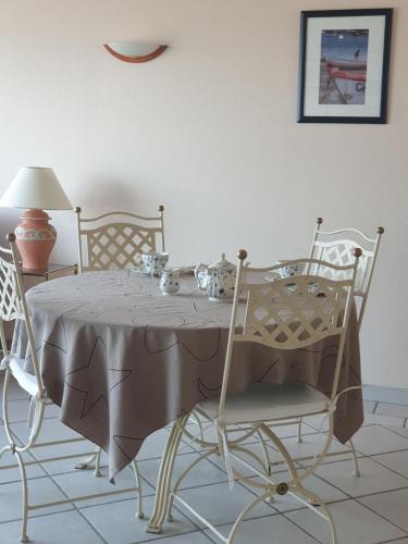 a dining room table with chairs and a table and a lamp at Le Guépratte in Granville