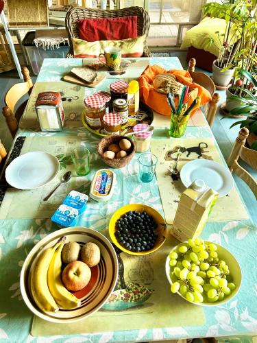 a table with plates of food and fruit on it at 2 CHAMBRES B&B PRÈS DE L'AÉROPORT ET DU MEETT in Blagnac