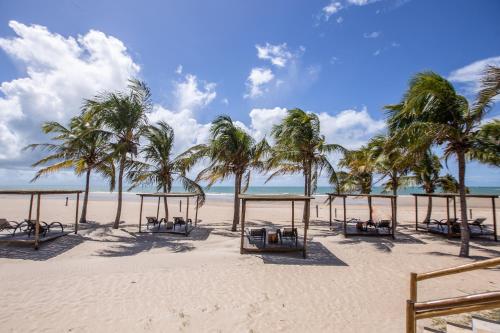 uma praia com um monte de mesas e palmeiras em Vila Vagalume em Trairi