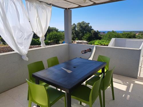 een blauwe tafel en groene stoelen op een balkon bij Apartment Mimosa-Olib HR in Olib