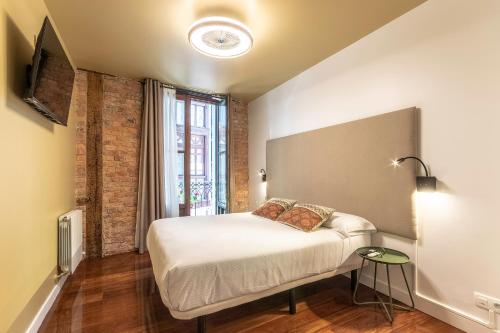 a small bedroom with a bed and a window at Victorooms in Bilbao