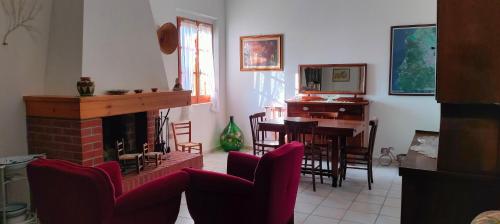 salon z kominkiem, stołem i krzesłami w obiekcie Il Villino della Nonna w mieście Arbus