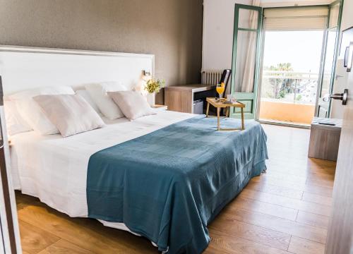 a bedroom with a large bed with a blue blanket on it at Hotel Planas in Salou