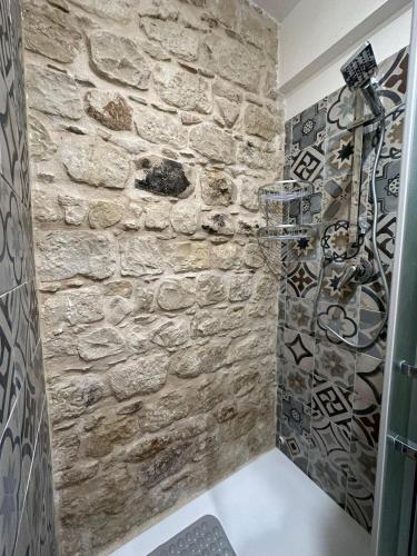 a shower in a bathroom with a stone wall at IL RIFUGIO BAROCCO in Modica