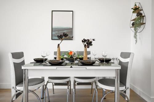 uma mesa de jantar branca com cadeiras e uma parede branca em Ideal Lodgings In Urmston em Urmston