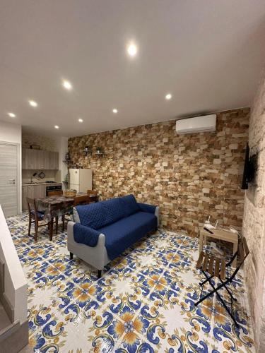 uma sala de estar com um sofá azul e uma parede de tijolos em IL RIFUGIO BAROCCO em Modica