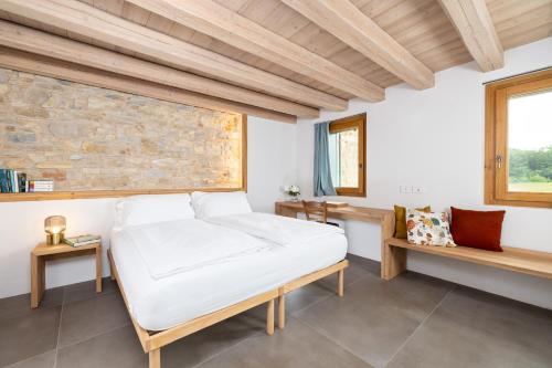 een slaapkamer met een wit bed en een stenen muur bij B&B Le Zucche in Belluno