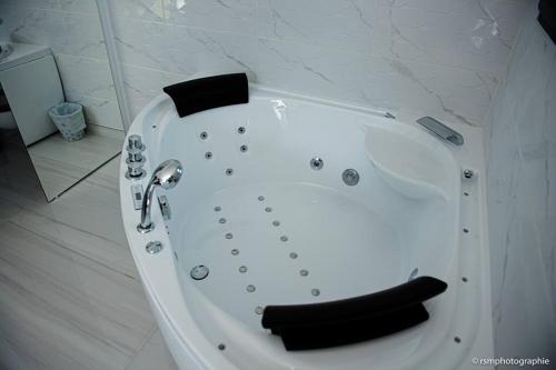 La salle de bains est pourvue d'une baignoire blanche avec un siège noir. dans l'établissement Villa Honoré bord mer/ jacuzzi, au Grau-dʼAgde