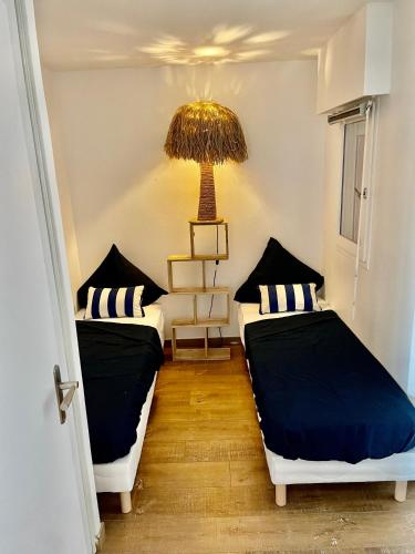 - 2 lits dans une petite chambre avec une lampe dans l'établissement Le rayon vert, à Six-Fours-les-Plages