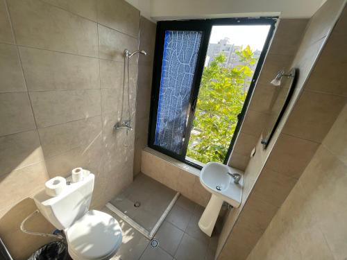 baño con aseo y lavabo y ventana en Sanremo Hotel Restorant, en Durrës