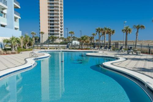 a swimming pool with palm trees and a building at Emerald Dolphin unit 610 in Pensacola Beach