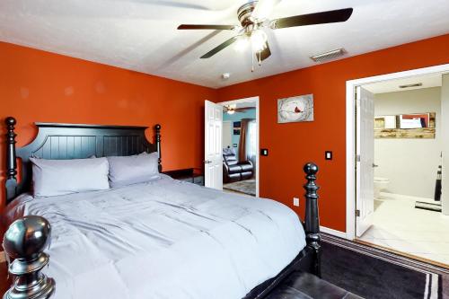 a bedroom with orange walls and a bed with a ceiling fan at Sundial Sanctuary in Fort Myers