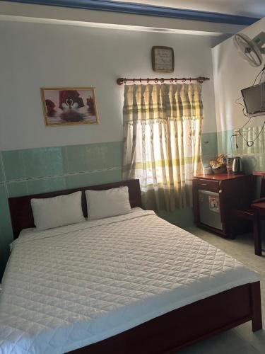 a bedroom with a bed with white sheets and a window at Minh Ha Hotel in La Gi