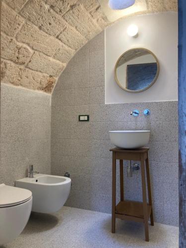 een badkamer met een wastafel, een toilet en een spiegel bij Dimora le Picciose in Ostuni