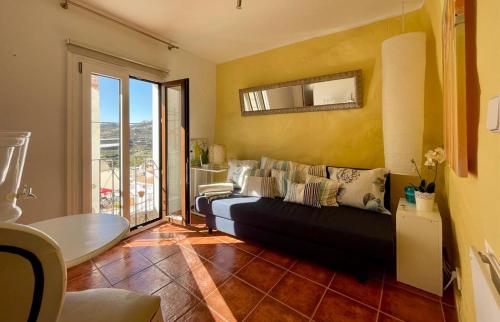 uma sala de estar com um sofá preto e uma parede amarela em Small village house with beautiful sea views em Torrox