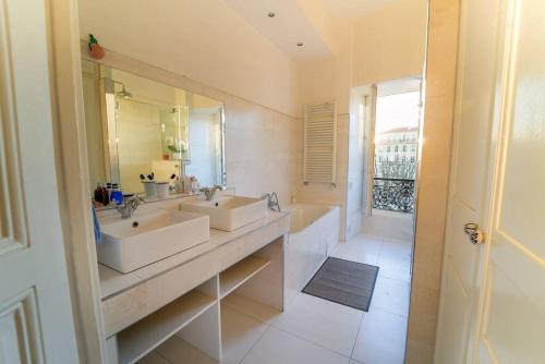 une salle de bain avec deux lavabos et un grand miroir dans l'établissement S8 Grimaldi Suite Centrale 5min de la Mer AC, à Nice
