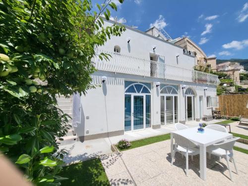 Casa blanca con mesa y sillas blancas en Cottage L'Americano, en Positano