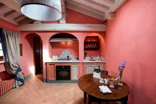 a kitchen with red walls and a wooden table at Borgo Pignano Tuscany in Pignano