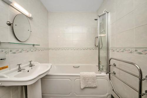 een witte badkamer met een wastafel en een bad bij Finest Retreats - Hambleton Hall Apt in Thirsk