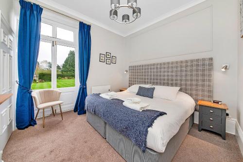 a bedroom with a bed with blue curtains and a window at Finest Retreats - Hambleton Hall Apt in Thirsk