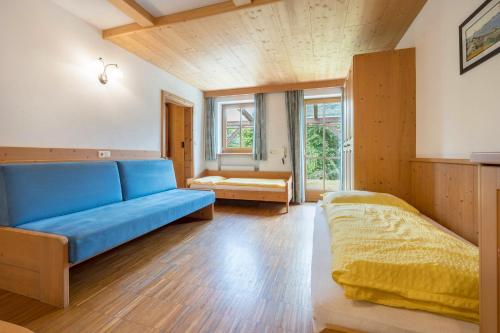 uma sala de estar com um sofá azul e uma cama em Lindenhof Apt 5 em Vandoies