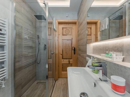 a bathroom with a white sink and a shower at SASÓWKA APARTAMENT in Maniowy