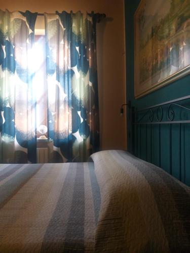a bedroom with a bed and a window with curtains at Mosci's Bed & Beer in San Damiano dʼAsti