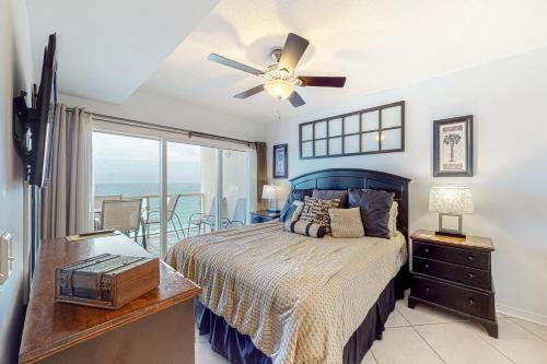 a bedroom with a bed with a ceiling fan and a window at Emerald Isle 1105 in Pensacola Beach