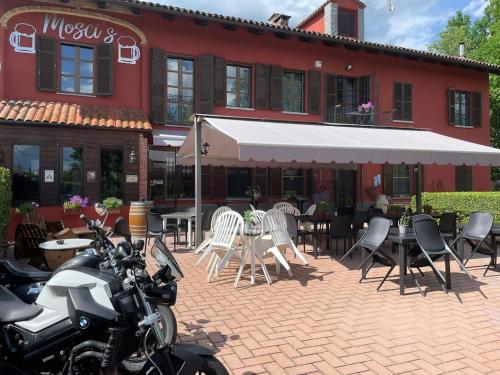 une moto garée devant un immeuble avec des tables et des chaises dans l'établissement Mosci's Bed & Breakfast, à San Damiano dʼAsti