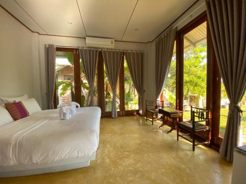 um quarto com uma cama branca e janelas grandes em BaanSuk Sukhothai Resort em Sukhothai