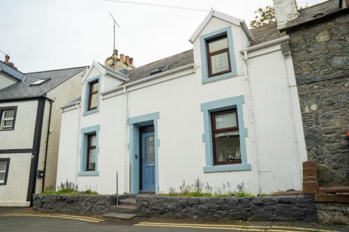 una casa bianca con finestre blu di The Portpatrick Pad - A cosy 3 bed cottage, w. sea views & garden office a Portpatrick