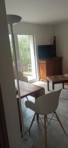 un salon avec une table, des chaises et une télévision dans l'établissement Au coin du potager, à Le Rouret