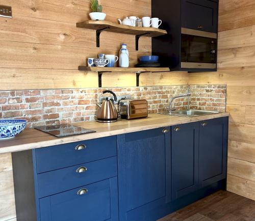 uma cozinha com armários azuis e um lavatório em TVF Stable Suites em Nether Stowey