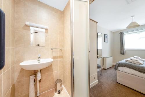 a bathroom with a sink and a shower and a bed at Finest Retreats - Ryedale Hall Cottage in Thirsk