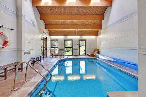 a swimming pool with a wooden ceiling and an indoor swimming pooliterator at Finest Retreats - Swaledale Hall Cottage in Thirsk