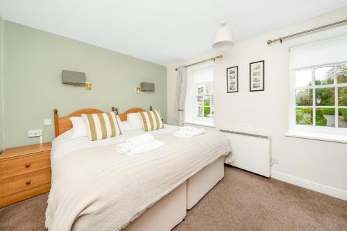 a bedroom with a large bed and two windows at Finest Retreats - Swaledale Hall Cottage in Thirsk