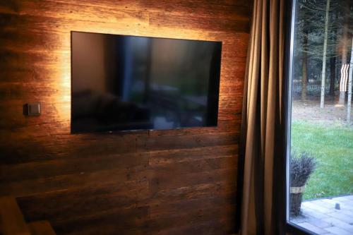 a flat screen tv on a wooden wall with a window at Apartamenty Leśne Historie in Gołuchów