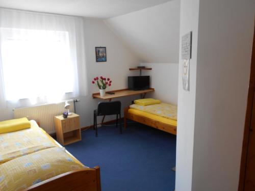 Habitación pequeña con 2 camas y escritorio. en Árpád Panzió, en Győr