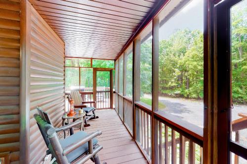 a screened porch with rocking chairs and windows at Whistle and Quill Lodge in Swanton
